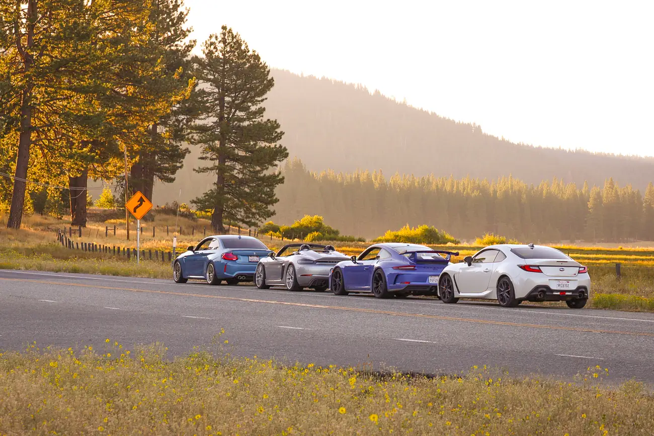 Four cars lined up on a Sierra roadside at golden hour